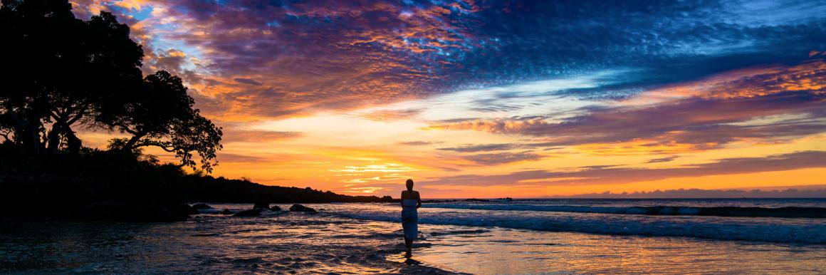 Woman at sunrise on beach on island of Hawaii