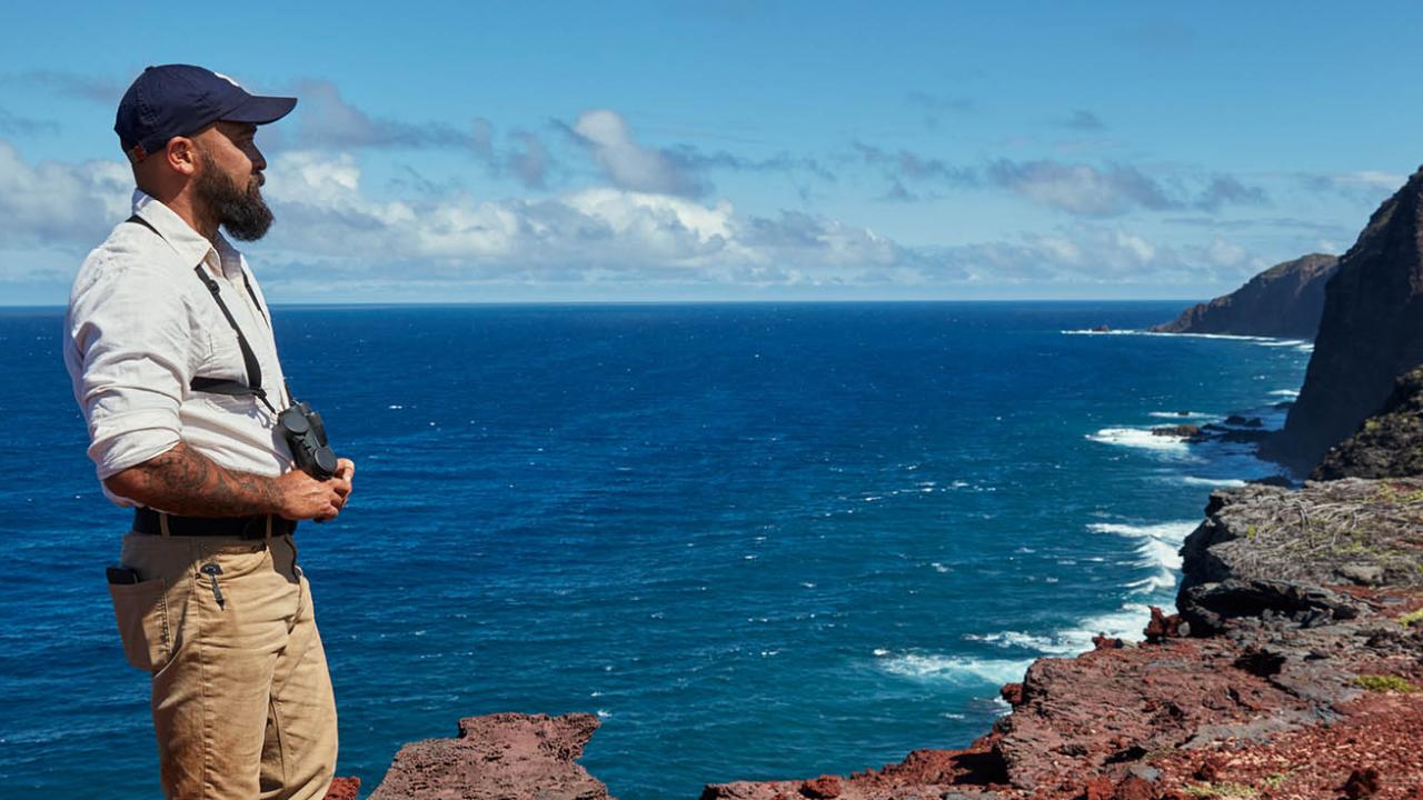 Man looking over cliff and ocean