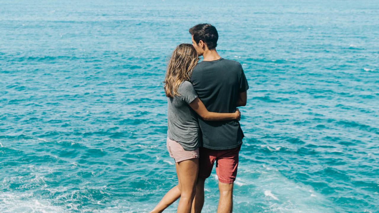 Couple embracing top of cliff overlooking ocean in Molokai