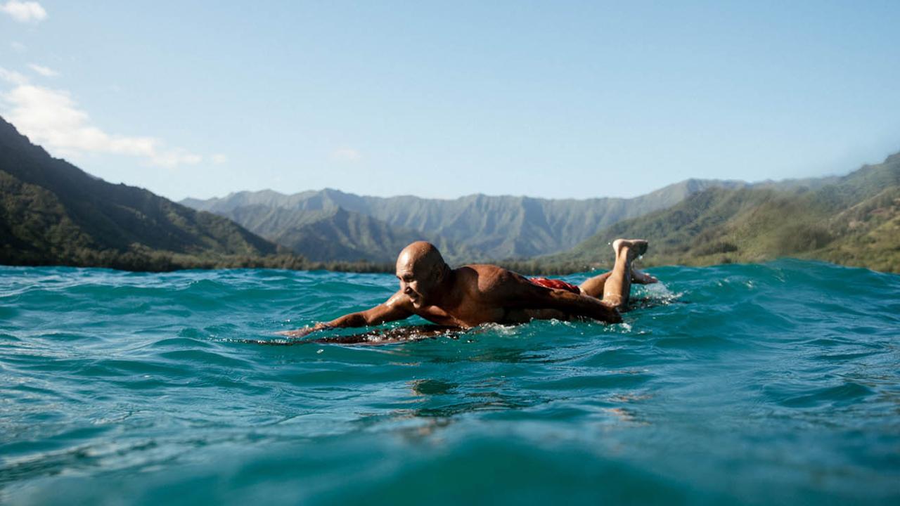 surfer on board in ocean with mountain background Oahu