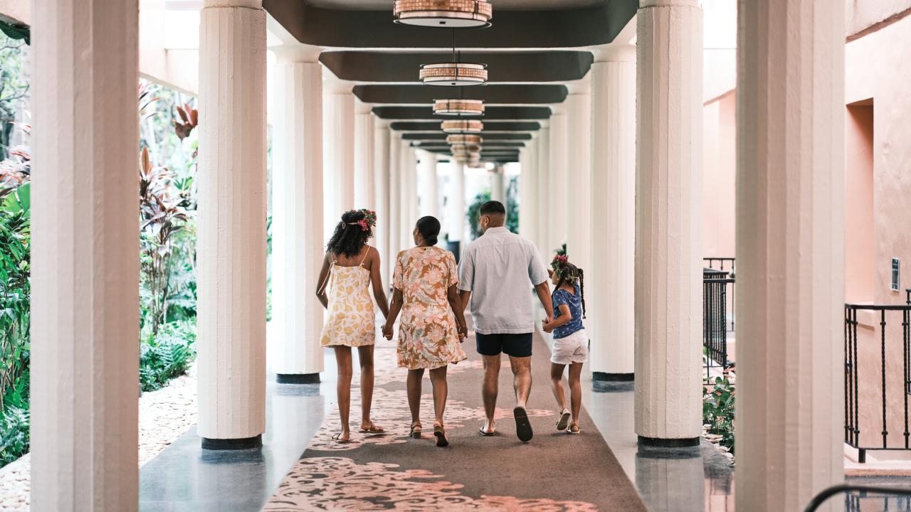 family walking down corridor lined with columns away from the camera