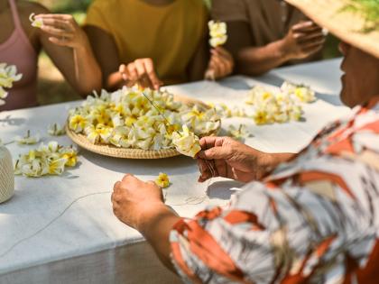 People make yellow plumeria lei during a workshop