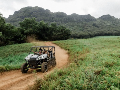 Jeep driving on a dirt trail with the heavy dense jungle greenery in the background
