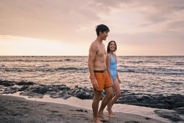 Couple walks on the beach at sunset