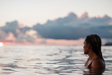 woman in ocean looking at sunset